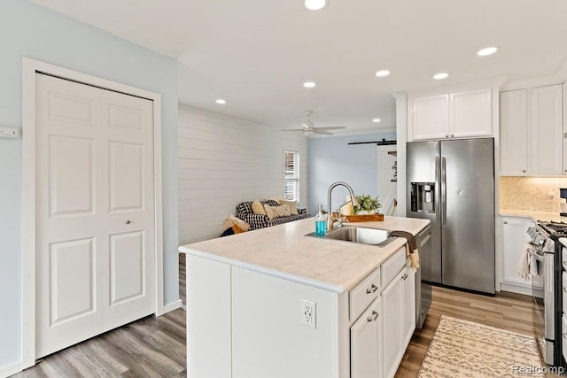1319 Rochester Rd, Leonard, MI 48367 - kitchen featuring stainless steel appliances, a sink, light wood-style flooring, a ceiling fan, and white cabinetry