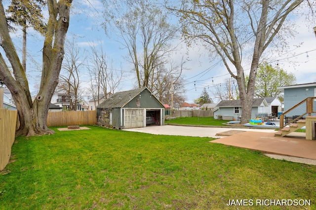 view of yard with a fenced backyard, an outdoor fire pit, an outbuilding, and a detached garage