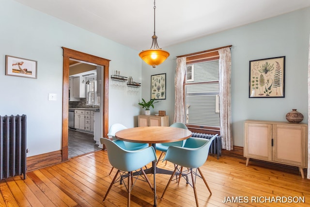 dining area with radiator heating unit, radiator, and light wood-style flooring