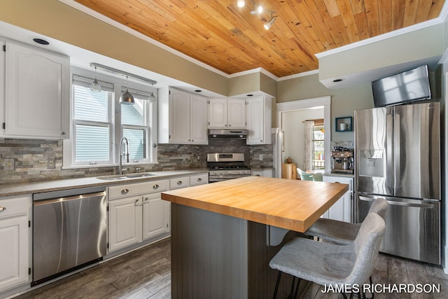 kitchen with a sink, wood counters, ornamental molding, stainless steel appliances, and white cabinetry