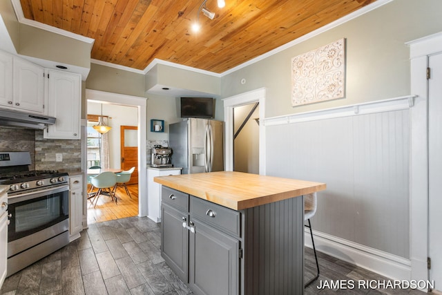kitchen with wood counters, ornamental molding, stainless steel appliances, and under cabinet range hood