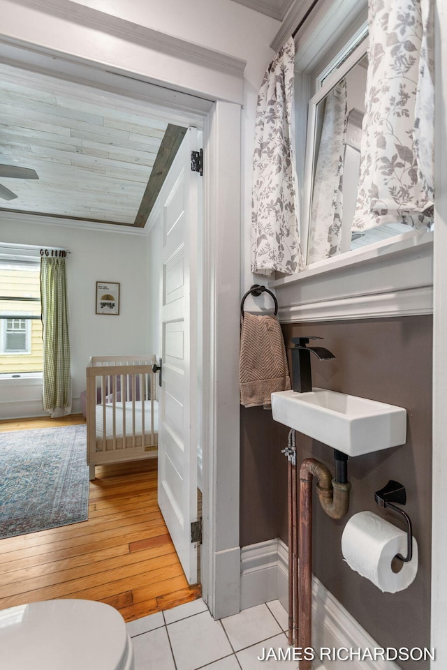 half bath featuring crown molding, a sink, toilet, tile patterned floors, and baseboards