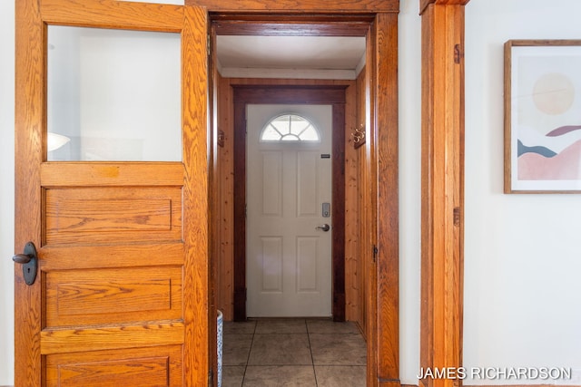 doorway featuring tile patterned flooring and crown molding