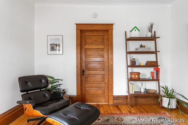 living area with ornamental molding and wood finished floors