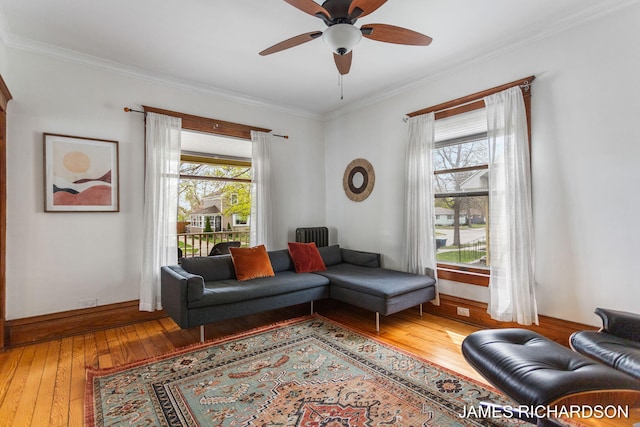 living room with crown molding, a ceiling fan, baseboards, and hardwood / wood-style flooring
