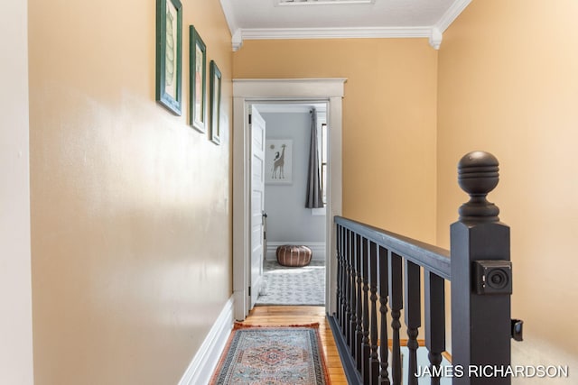 corridor with crown molding, wood finished floors, and an upstairs landing