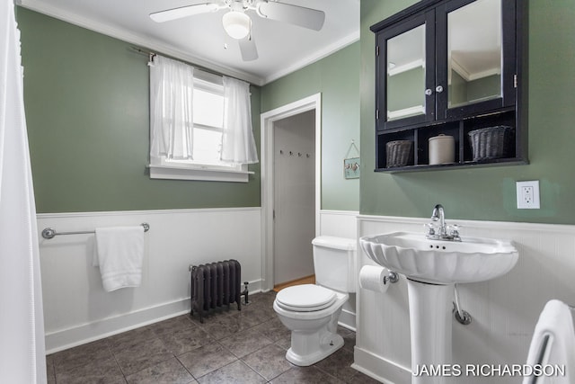 bathroom with crown molding, wainscoting, toilet, radiator, and a ceiling fan