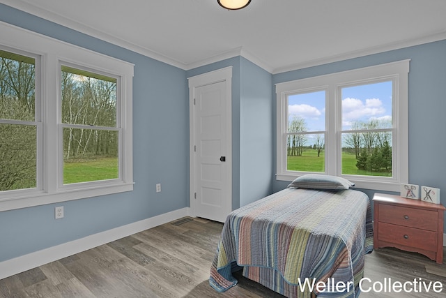 bedroom with crown molding, baseboards, wood finished floors, and visible vents