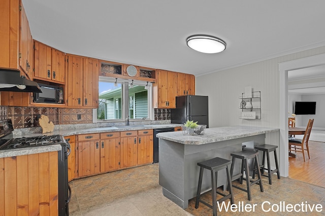 kitchen featuring light countertops, a sink, black appliances, and tasteful backsplash