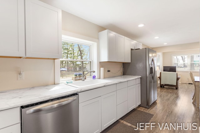 kitchen with appliances with stainless steel finishes, a sink, light wood finished floors, recessed lighting, and white cabinetry