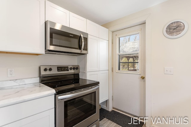 kitchen with light stone counters, white cabinetry, and appliances with stainless steel finishes