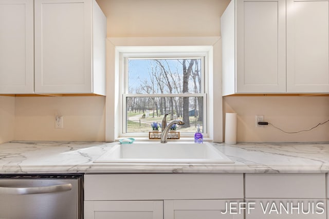 kitchen featuring a sink, light stone counters, stainless steel dishwasher, and white cabinetry