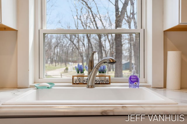 interior details with white cabinetry and a sink