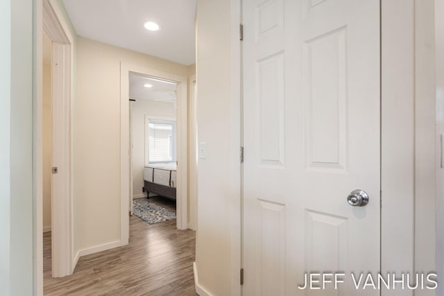 hallway featuring baseboards, recessed lighting, and wood finished floors