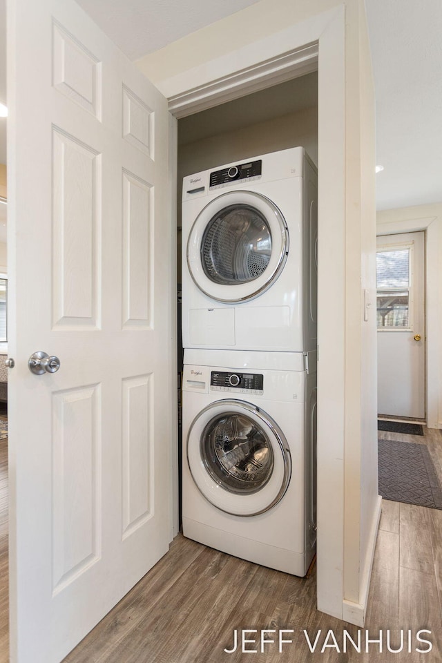 washroom featuring laundry area, wood finished floors, and stacked washer / dryer