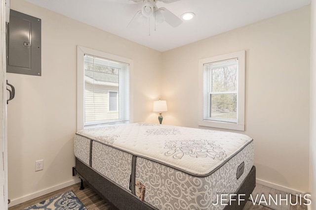 bedroom with baseboards, ceiling fan, wood finished floors, and electric panel