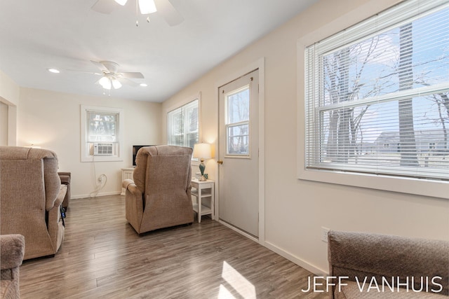 sitting room with baseboards, ceiling fan, wood finished floors, and cooling unit