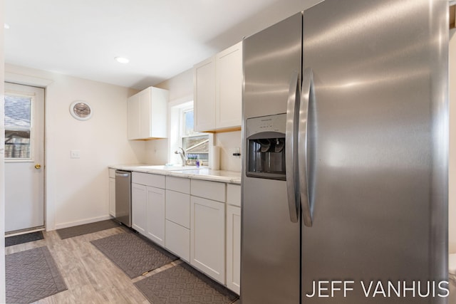 kitchen featuring appliances with stainless steel finishes, a sink, light countertops, plenty of natural light, and light wood-type flooring