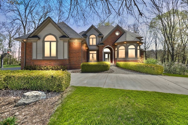 french country home featuring a front yard and brick siding