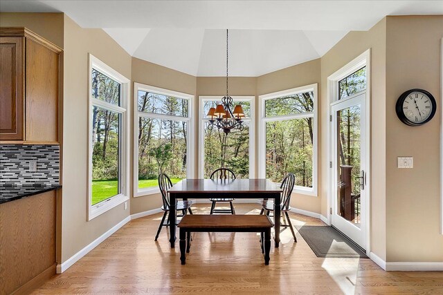 dining room with baseboards, a notable chandelier, a healthy amount of sunlight, and light wood-style floors