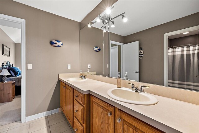full bath featuring double vanity, a sink, baseboards, and tile patterned floors