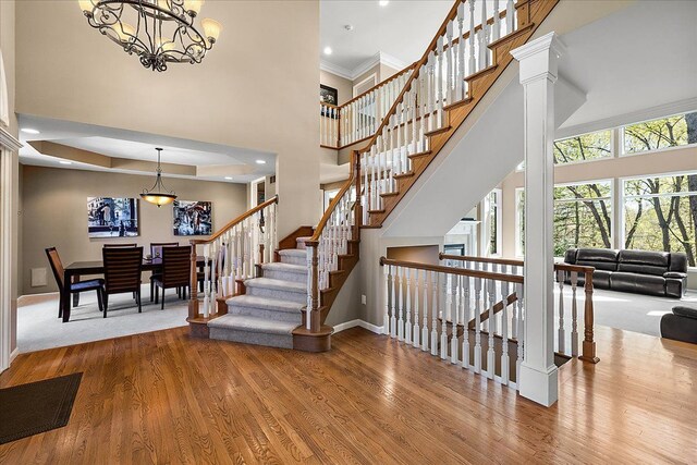 stairway with baseboards, a towering ceiling, and wood finished floors