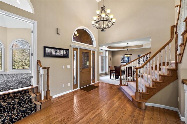 foyer with stairs, wood finished floors, and a notable chandelier
