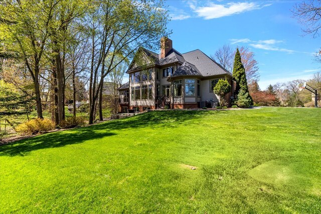 rear view of house featuring central AC unit, a yard, and a chimney