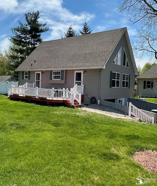 back of property with a yard, a deck, fence, and roof with shingles