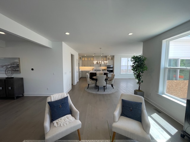 living area featuring a notable chandelier, dark wood finished floors, recessed lighting, baseboards, and visible vents