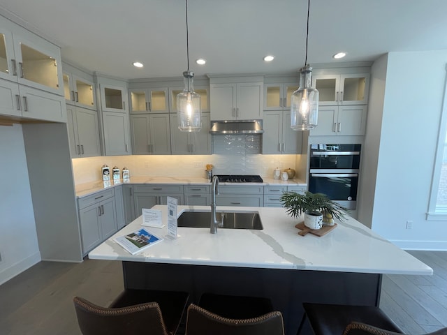 kitchen featuring a sink, baseboards, tasteful backsplash, and wood finished floors