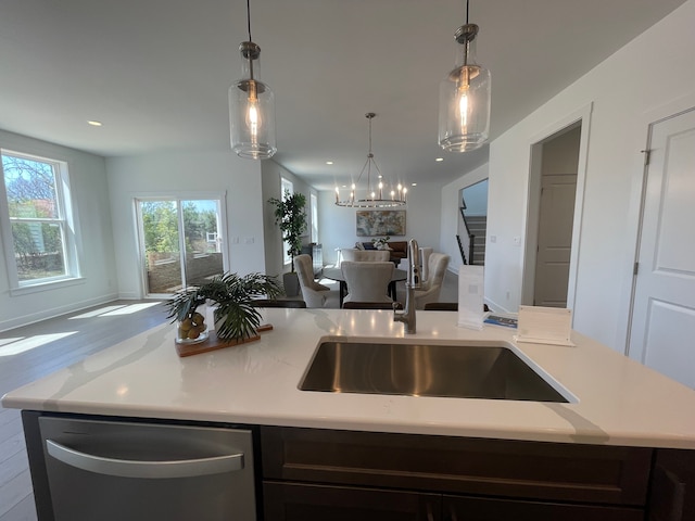 kitchen featuring stainless steel dishwasher, open floor plan, a sink, and light countertops
