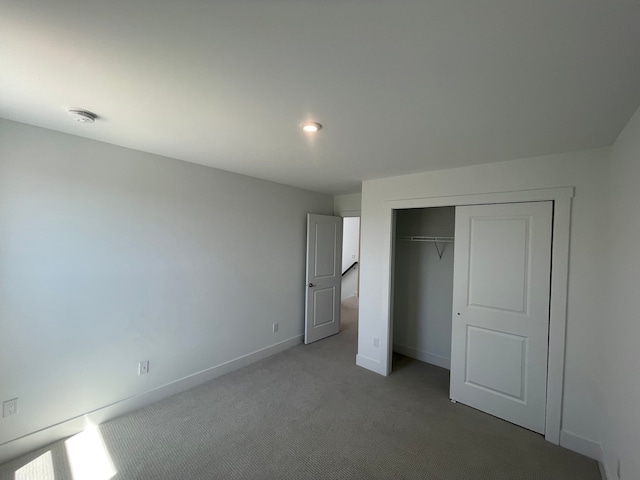 unfurnished bedroom featuring baseboards, carpet, and a closet