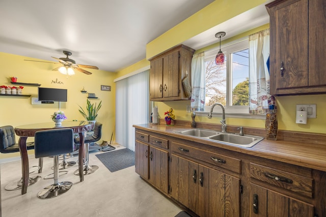 kitchen with a sink, a ceiling fan, and hanging light fixtures