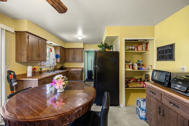 kitchen featuring black appliances, a sink, light countertops, hanging light fixtures, and brown cabinets
