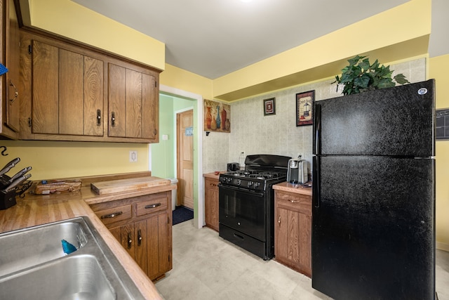 kitchen featuring black appliances, butcher block countertops, and brown cabinets