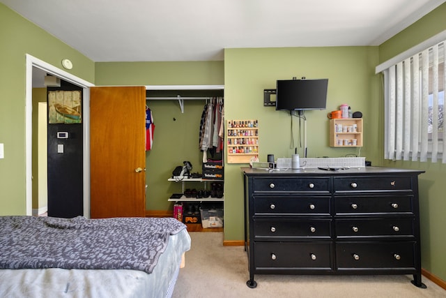 bedroom with a closet, light colored carpet, and baseboards
