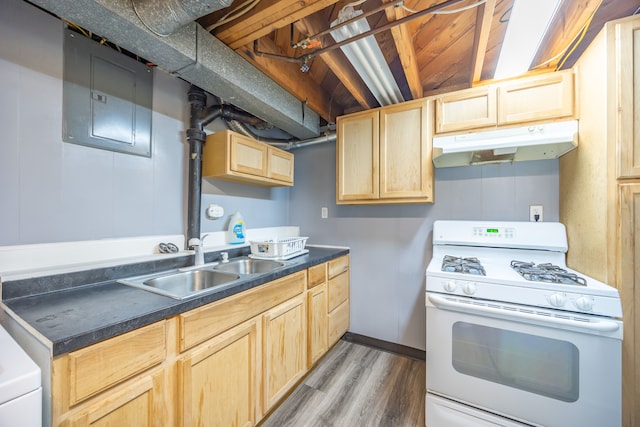 kitchen with white gas stove, light brown cabinetry, under cabinet range hood, a sink, and dark countertops