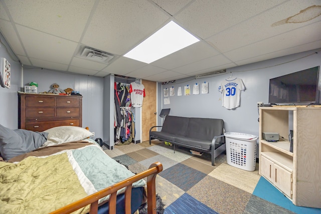 carpeted bedroom featuring a drop ceiling