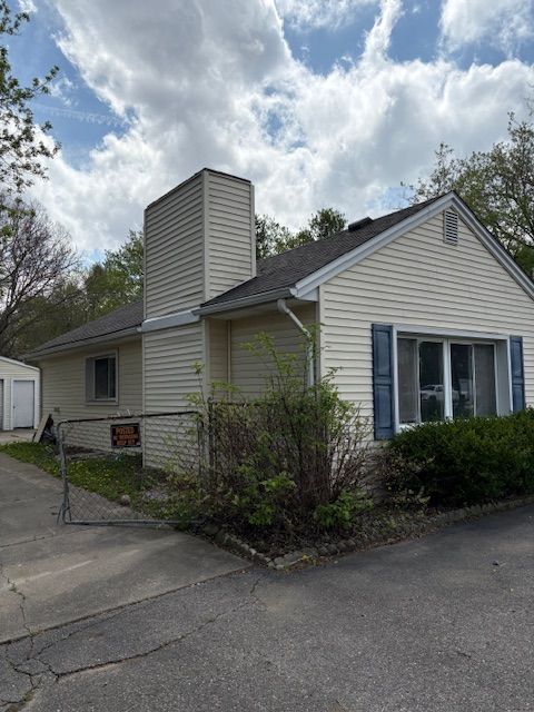 view of side of home with a garage, fence, and a chimney