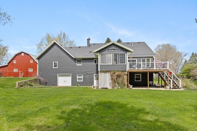 rear view of property featuring a lawn, a wooden deck, a chimney, stairs, and a barn