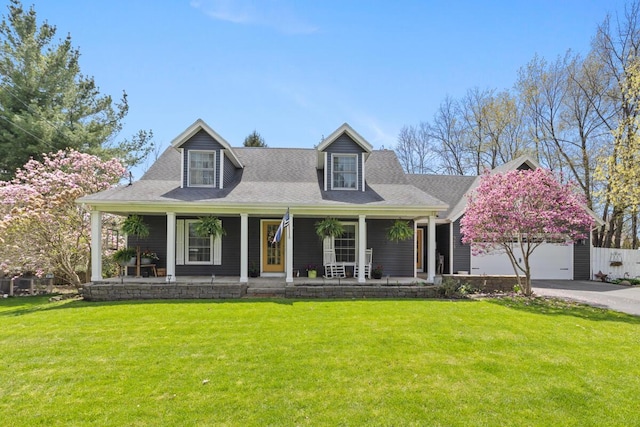 view of front of house featuring a garage, covered porch, and a front lawn