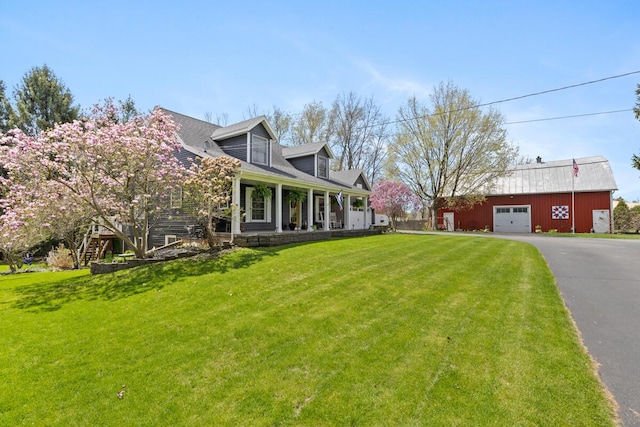 exterior space featuring an outbuilding, a yard, covered porch, and aphalt driveway