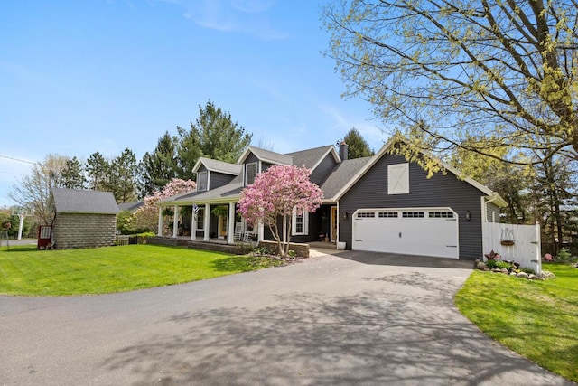 view of front of property with covered porch, driveway, a chimney, a garage, and a front lawn