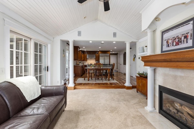 living room featuring lofted ceiling, light carpet, a fireplace, ceiling fan, and ornate columns