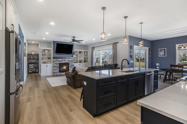 46140 Finch St, Mattawan, MI 49071 - kitchen with appliances with stainless steel finishes, a sink, dark cabinets, a stone fireplace, and a healthy amount of sunlight