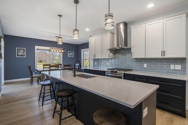 46140 Finch St, Mattawan, MI 49071 - kitchen featuring a sink, stainless steel gas stove, wall chimney exhaust hood, decorative backsplash, and a kitchen bar