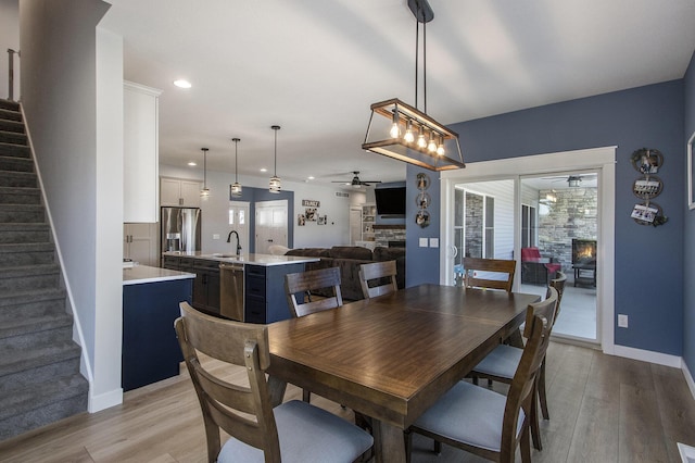46140 Finch St, Mattawan, MI 49071 - dining area with stairs, ceiling fan, a fireplace, and light wood-type flooring