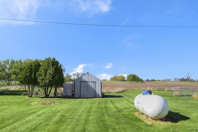 view of yard featuring an outdoor structure, a rural view, fence, and a storage unit