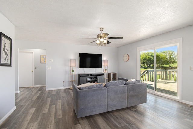 living room featuring ceiling fan, a textured ceiling, baseboards, visible vents, and dark wood-style floors